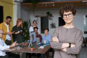 A female business owner stands in the foreground in front of her employees