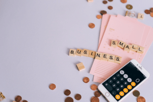 An iPhone calculator, pennies, paper and scrabble pieces spelling out "Small Business"